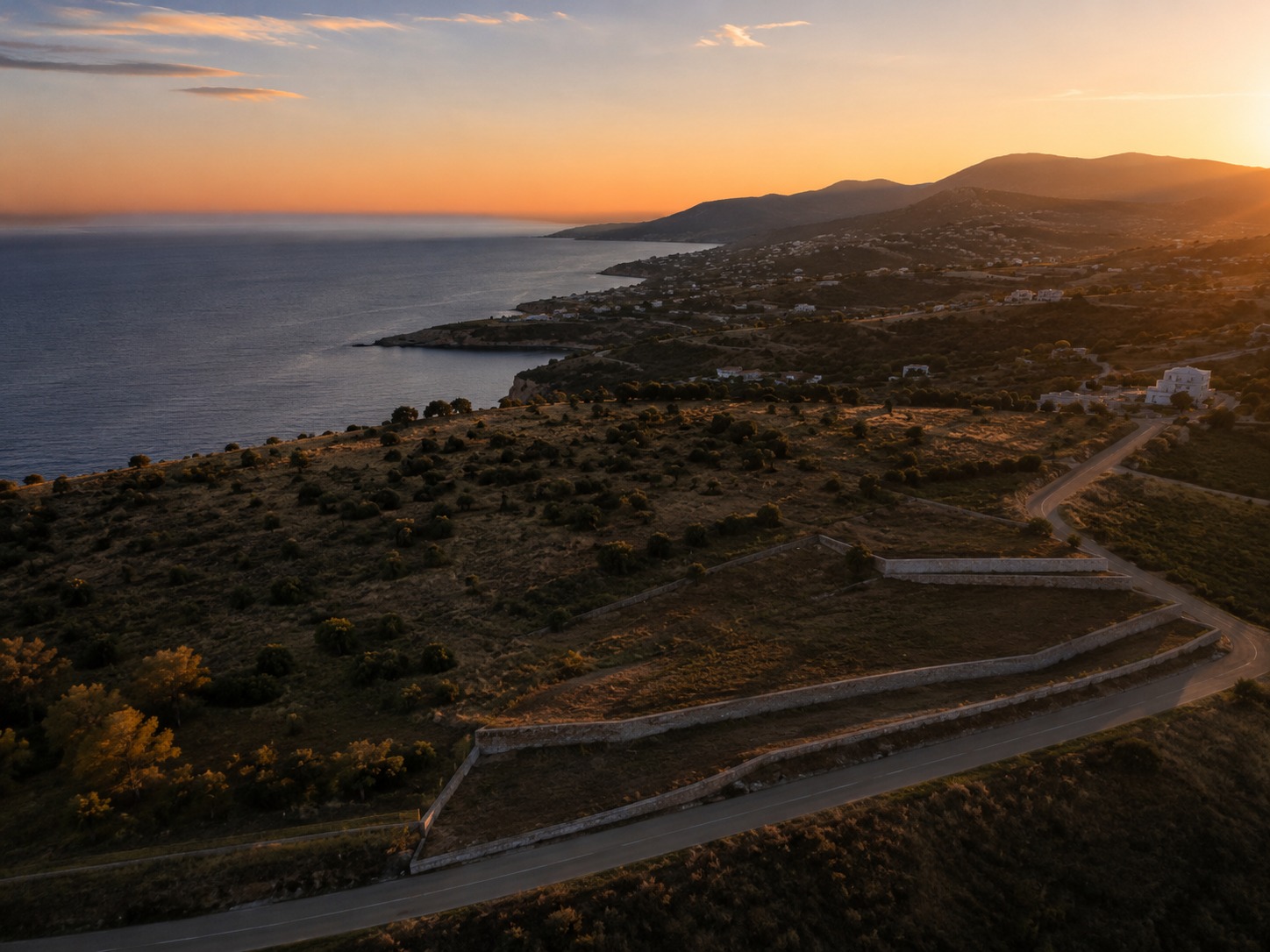 Aerial view of terraced coastal land plots above the sea at sunset